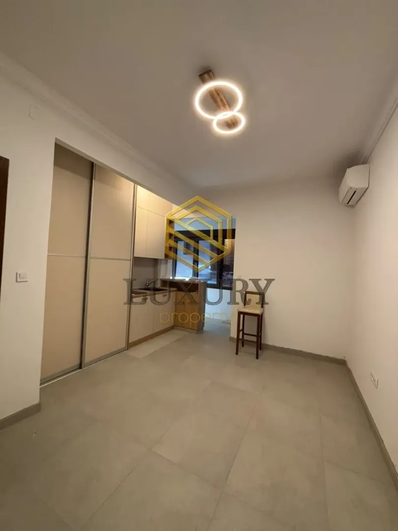 Living room with a kitchen in light tones.
