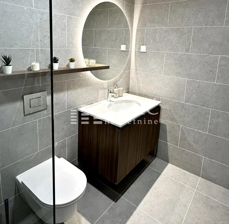 Modernly equipped bathroom with a washbasin, mirror, and toilet.
