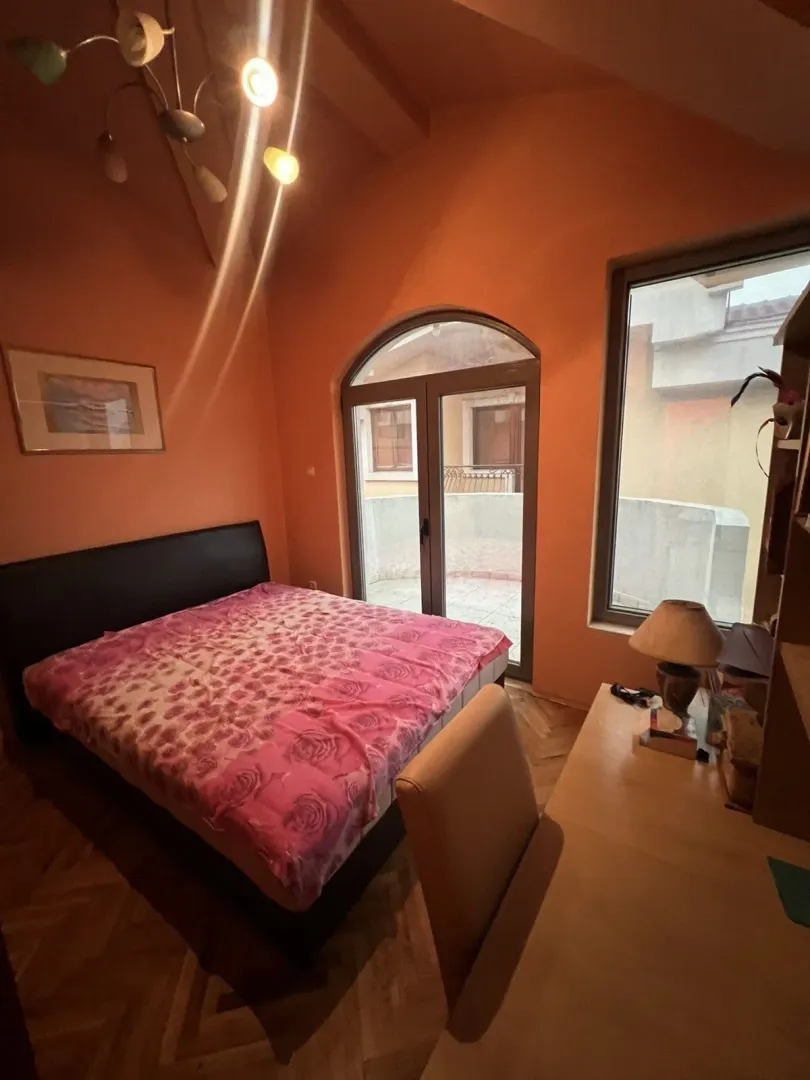 Spavaća soba sa narandžastim zidovima, bračnim krevetom i izlazom na balkon.