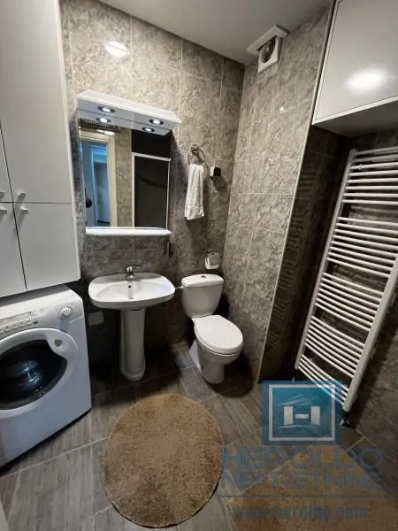 Compact bathroom with a washbasin, toilet, washing machine, and towel radiator.