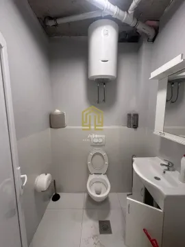 A small bathroom with a toilet, sink, and water heater. - image 8