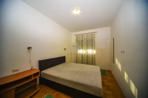 Bedroom with a double bed, wooden parquet flooring, and a window with curtains. - image 6