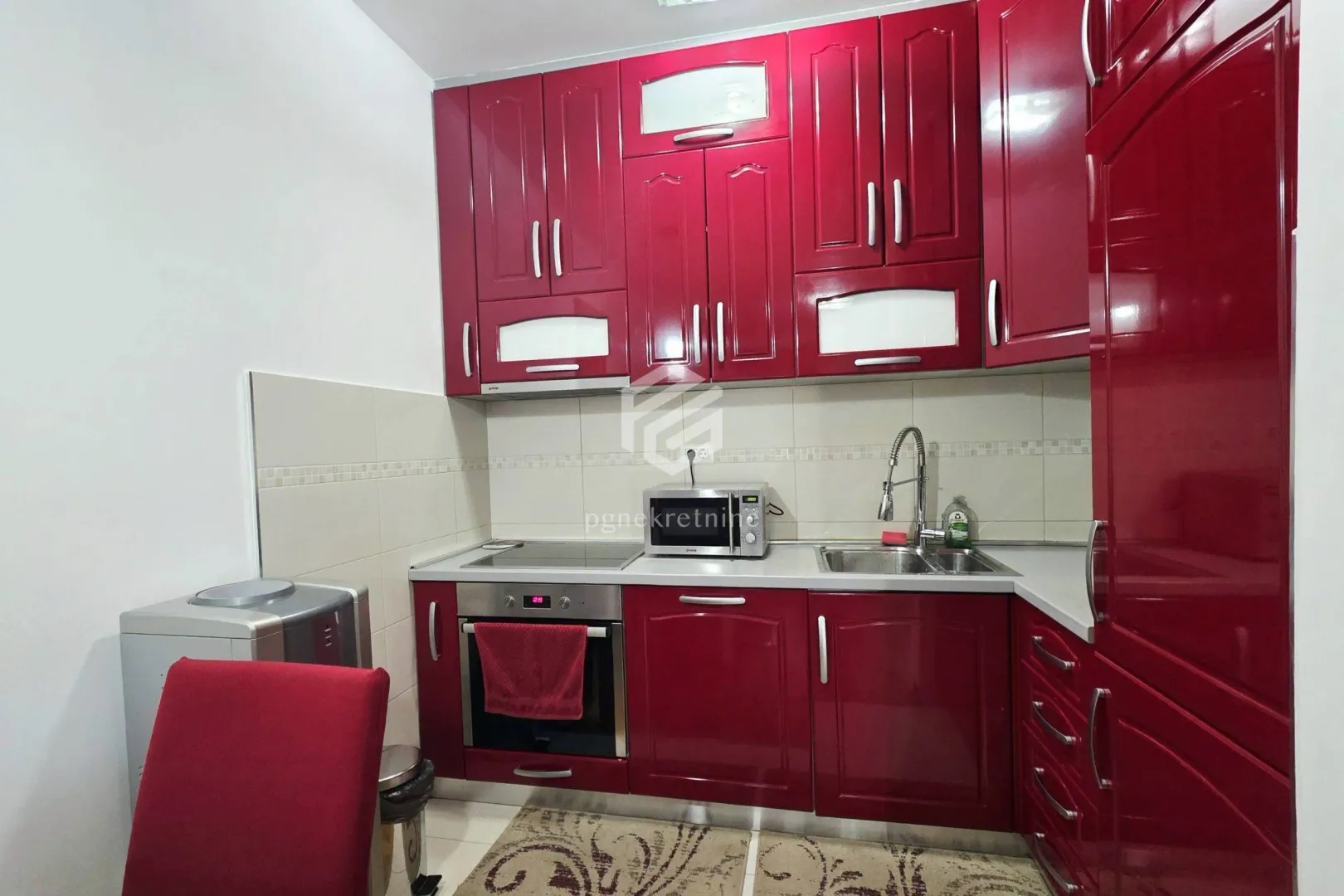 Kitchen equipped with red cabinets and built-in appliances.