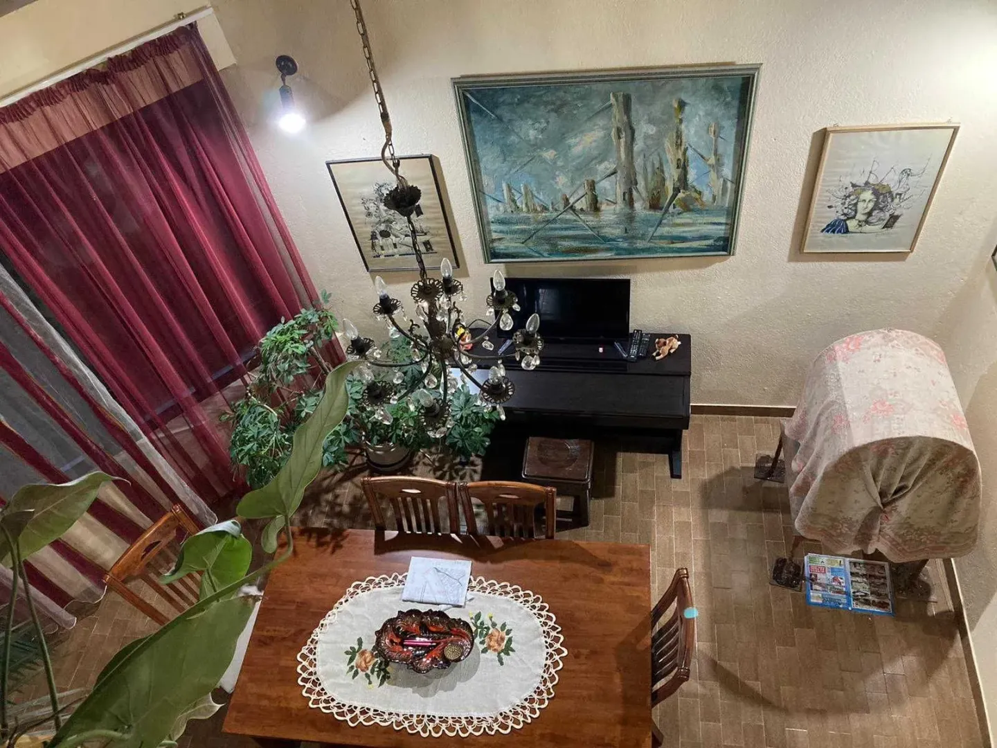 Pogled odozgo na dnevni boravak sa trpezarijskim stolom i umjetničkim slikama na zidu.