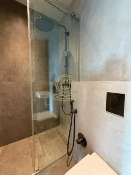 Modern bathroom with a walk-in shower and black fixtures. - image 9