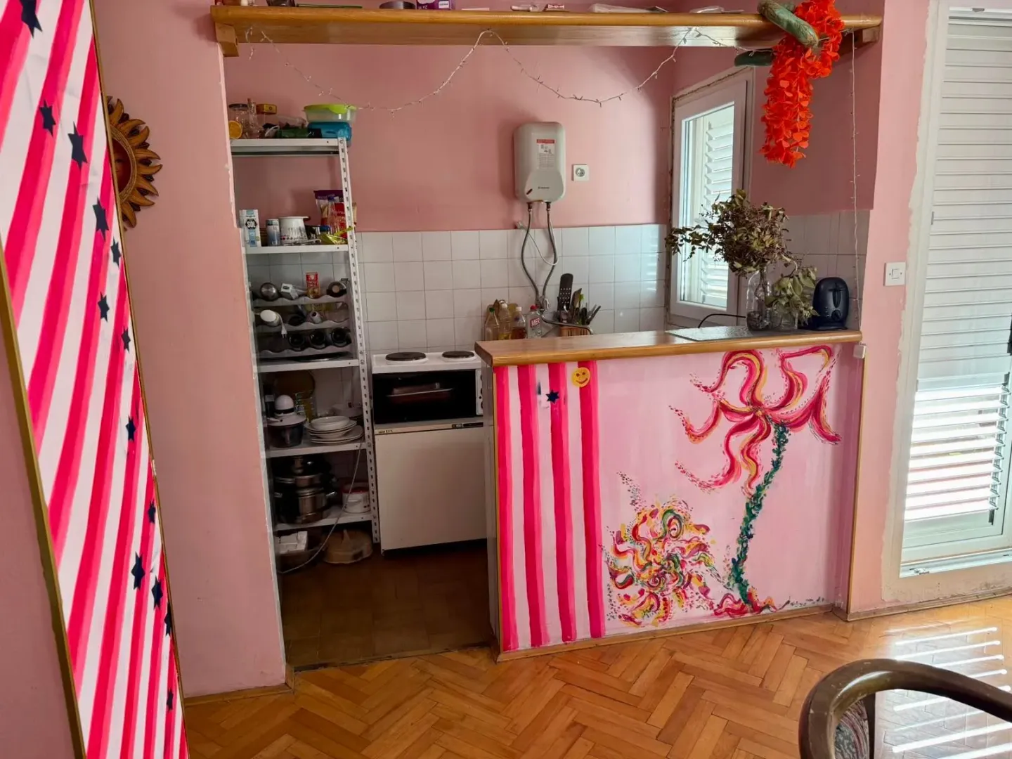 Manja kuhinja sa šankom i roze zidovima.