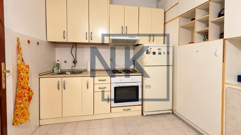Small kitchen with light-colored cabinets, a stove, and a refrigerator.
