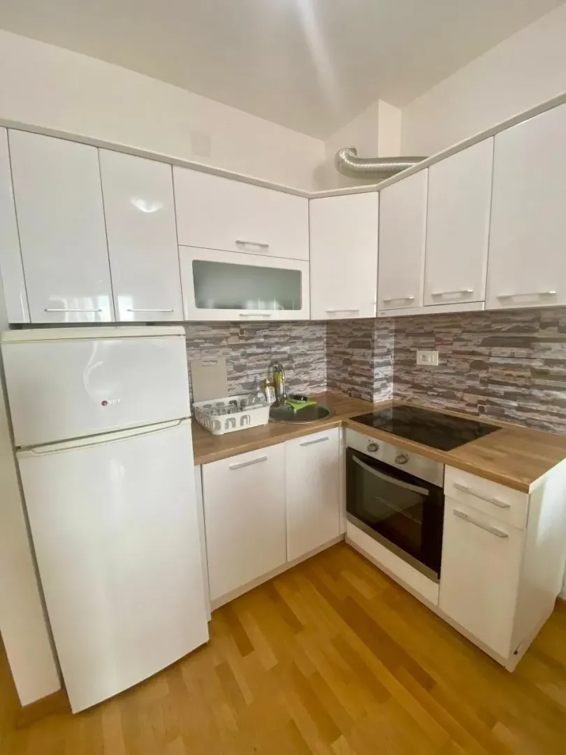Smaller white kitchen with wooden countertops and built-in appliances.