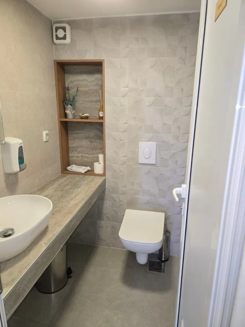 Modern bathroom equipped with a sink, wall-hung toilet, and a wall niche with shelving.