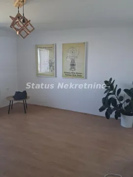 Dnevna soba sa drvenim podom, modernim lusterom i slikama na zidu. - image 3