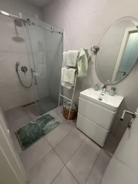 Modern bathroom with a walk-in shower, vanity, and mirror. - image 9