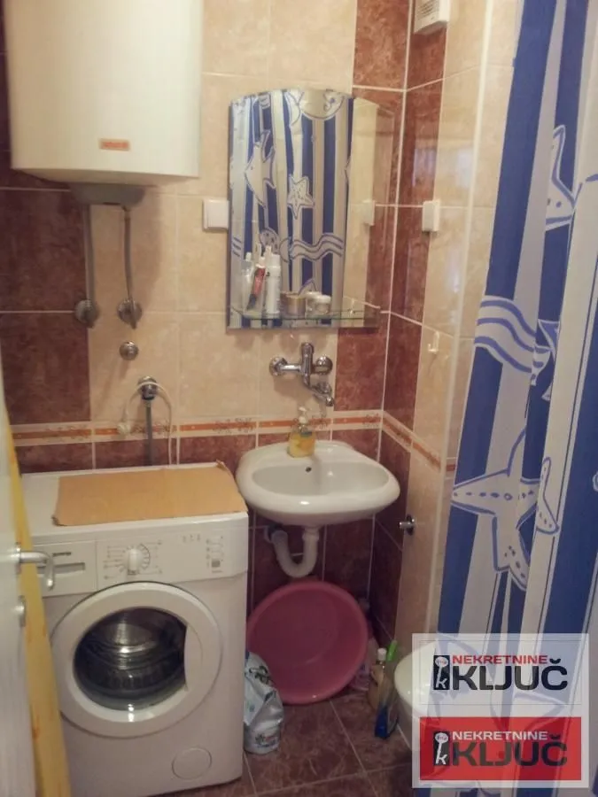 Manje kupatilo sa tuš kabinom, umivaonikom i veš mašinom.