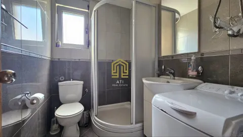 Small bathroom with a shower cabin, sink, toilet, and washing machine. - image 9