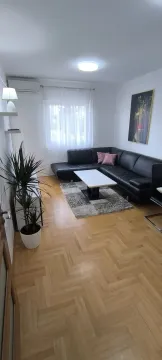 Bright living room with a black corner sofa and parquet flooring. - image 24