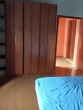 Bedroom with a large wooden wardrobe and a bed with blue bedding. - image 5