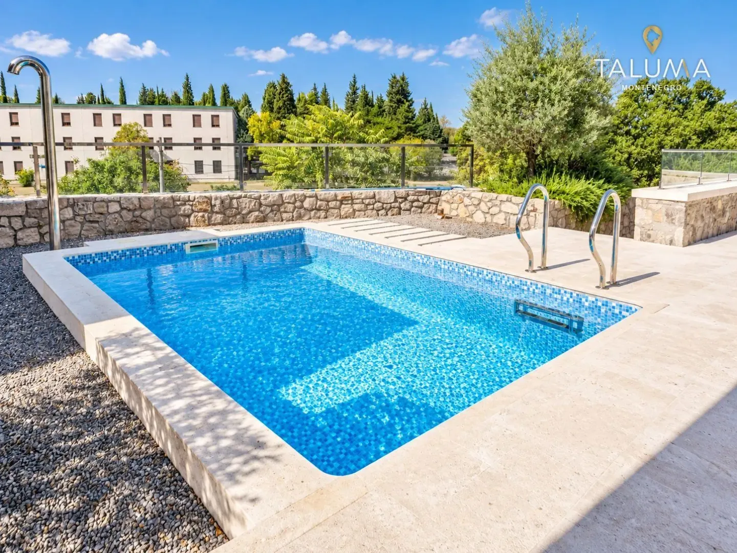 Outdoor swimming pool with a paved terrace and greenery view.