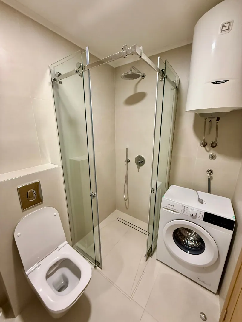 Savremeno opremljeno kupatilo sa tuš kabinom, WC šoljom i veš mašinom.