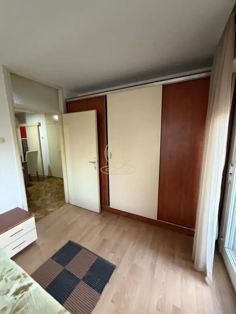 Spavaća soba sa velikim ugradnim garderoberom i laminatnim podom.