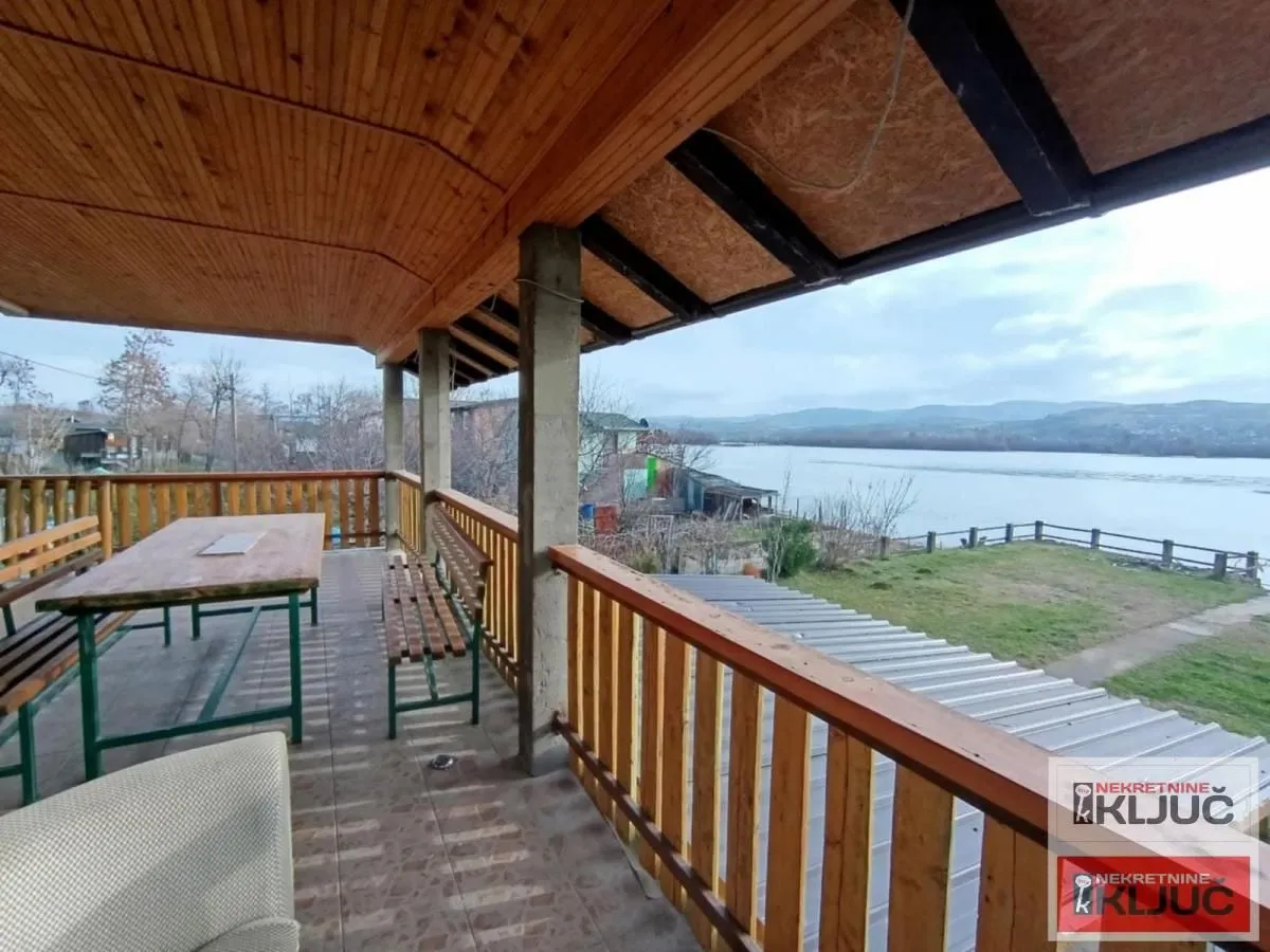 Covered terrace with wooden railing and river view.