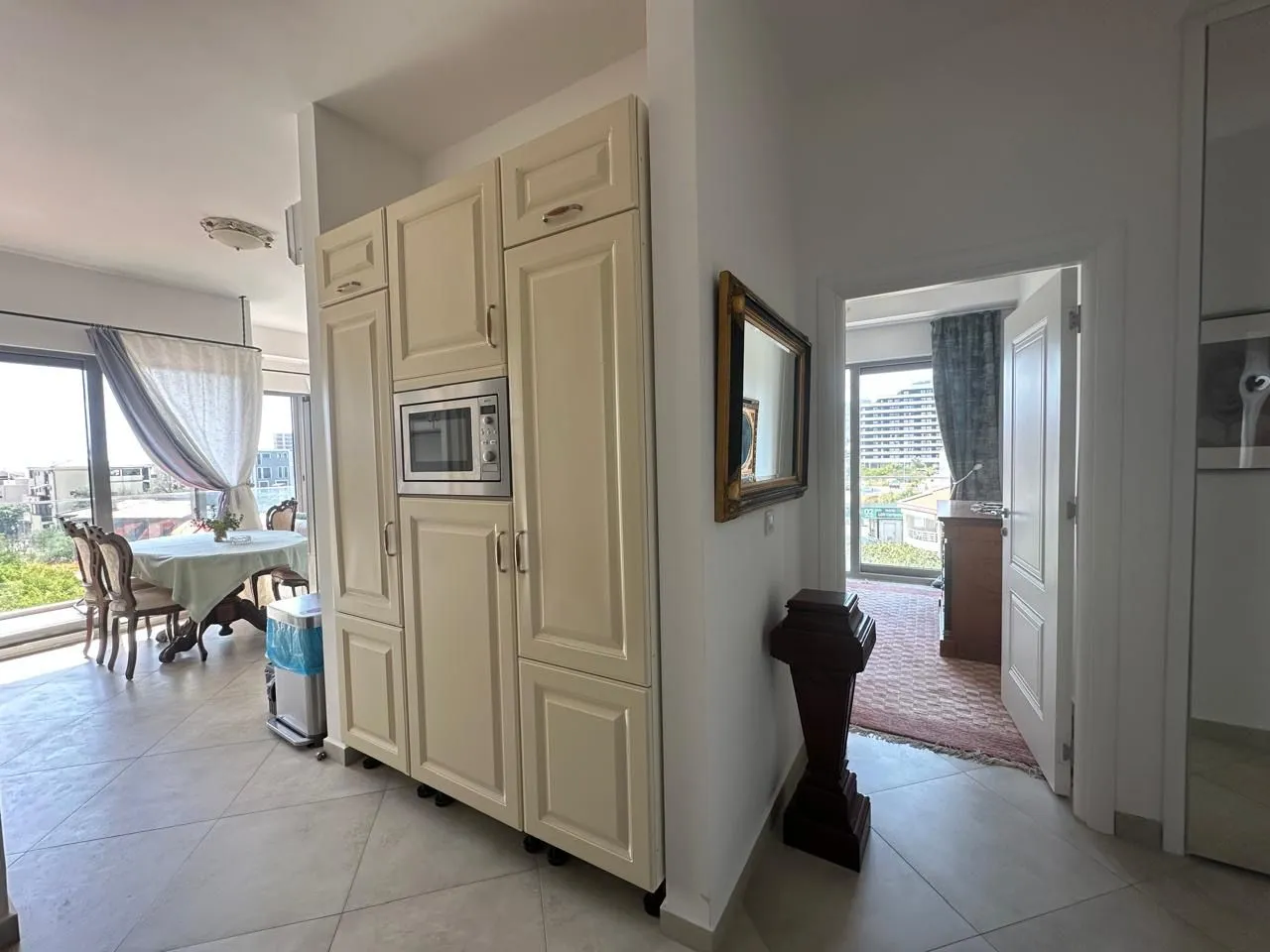 View of kitchen cabinetry with built-in appliances and a dining area in the background.
