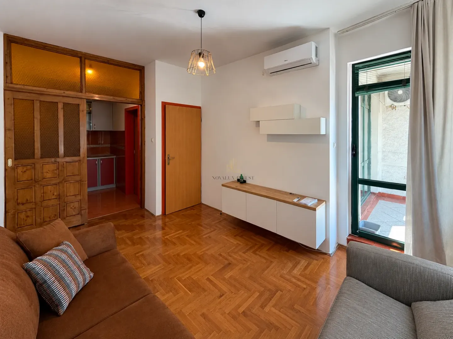 Living room with wooden parquet flooring, furniture, and access to the terrace.