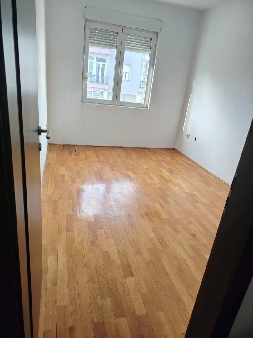 Prazna soba sa parketom i prozorom.
