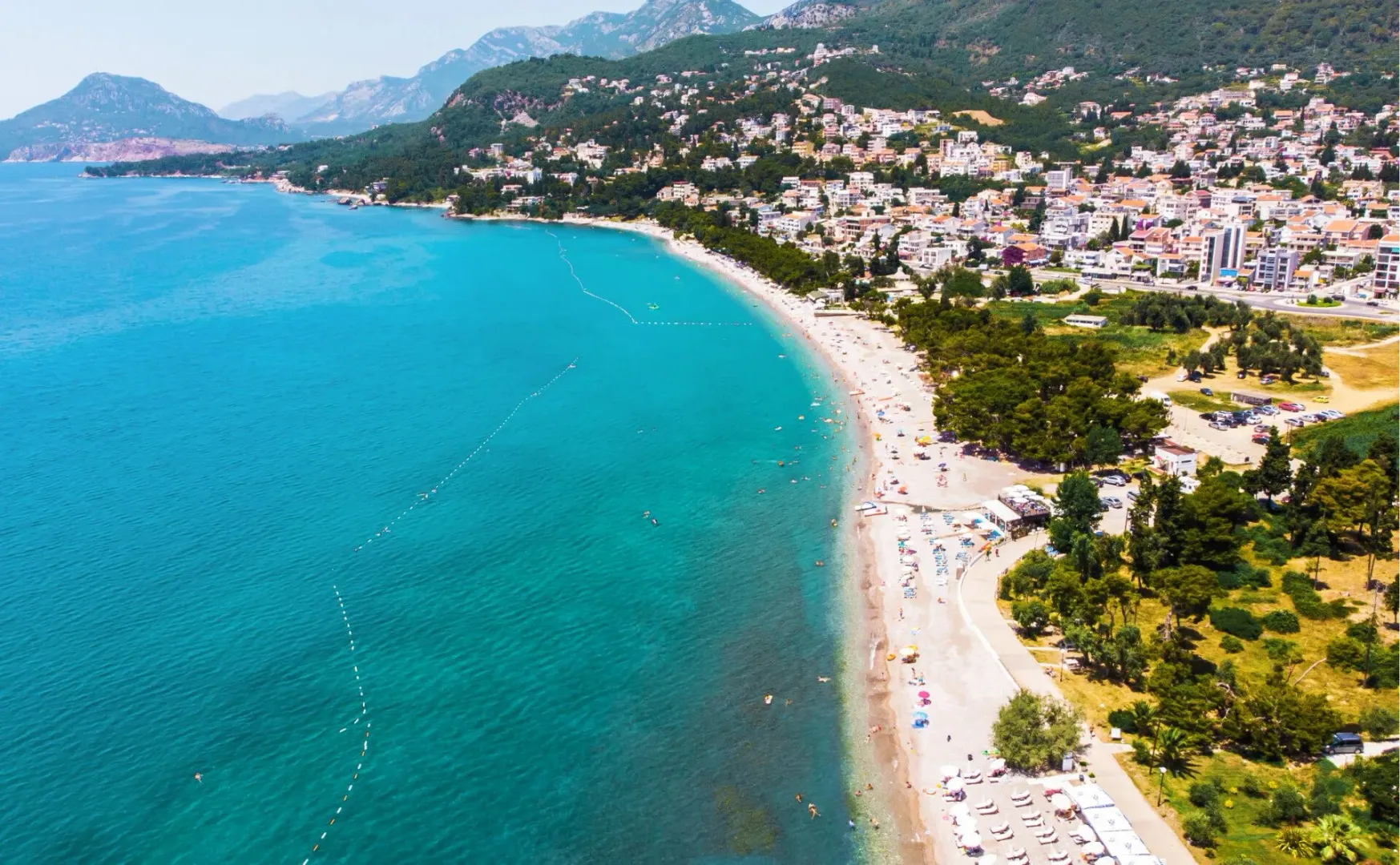 Pogled iz vazduha na obalu, plažu i naselje uz more.