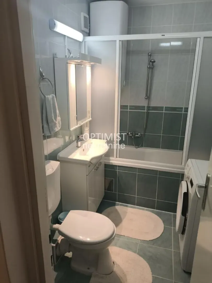 Bathroom with a shower cabin, washbasin, toilet, and washing machine.