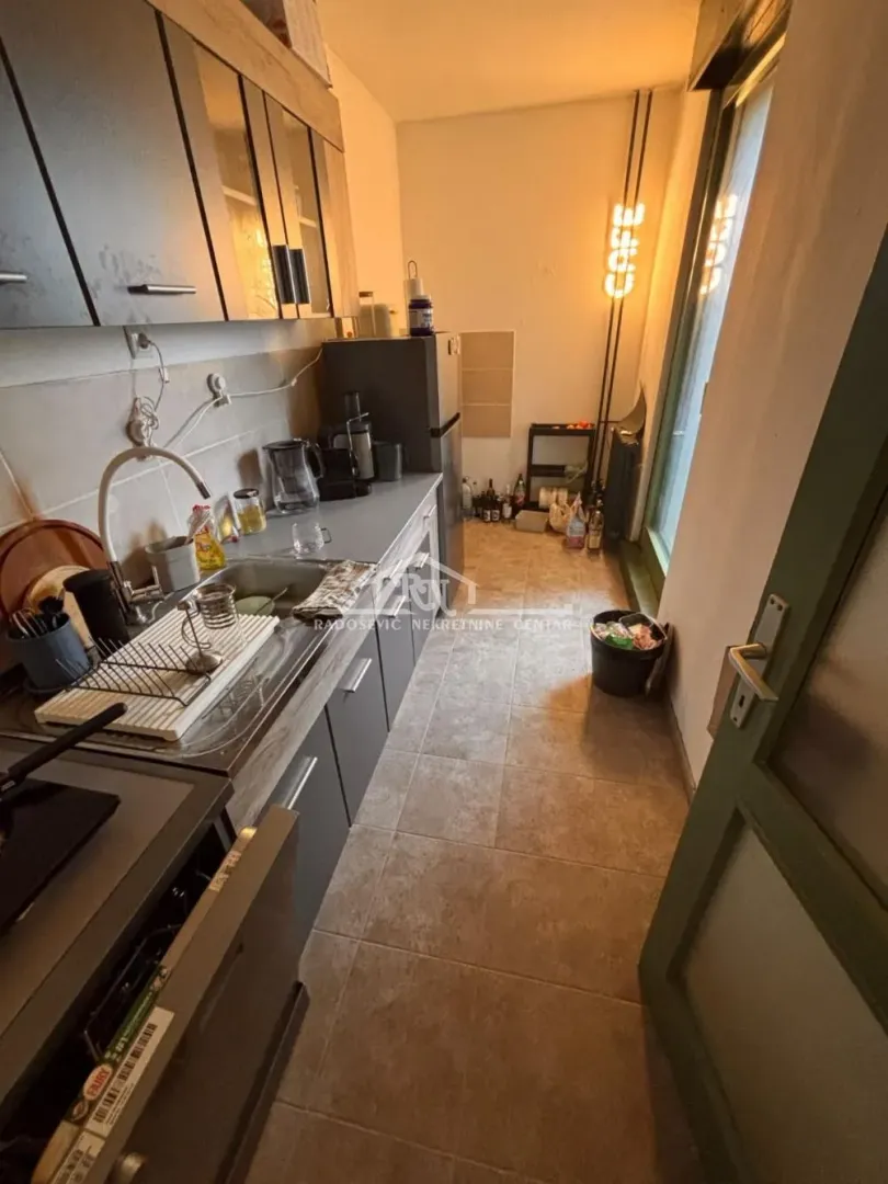 Compact kitchen with a sink, cabinetry, and a refrigerator.