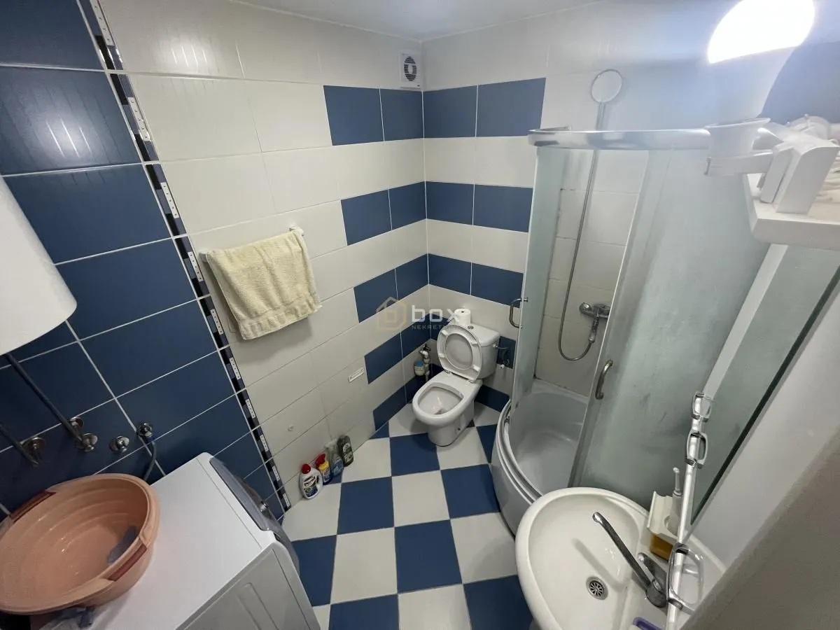 Bathroom equipped with a shower cabin, toilet, and sink with blue and white tiles.