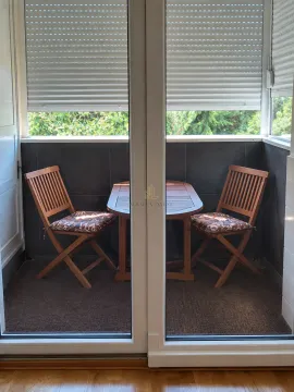 Small enclosed balcony with a wooden table and two chairs. - image 4