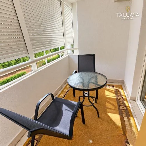 Zastakljeni balkon sa malim stolom i dve stolice.
