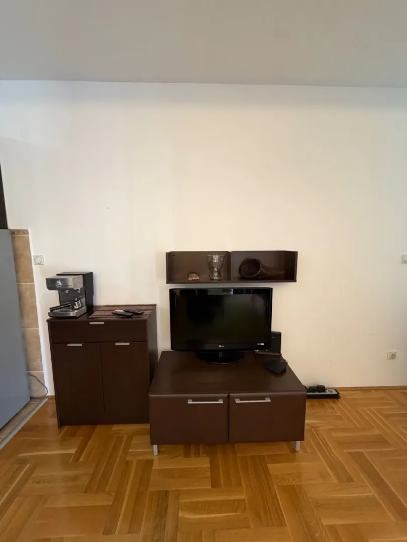 Dnevna soba sa TV komodom i aparatom za kafu.