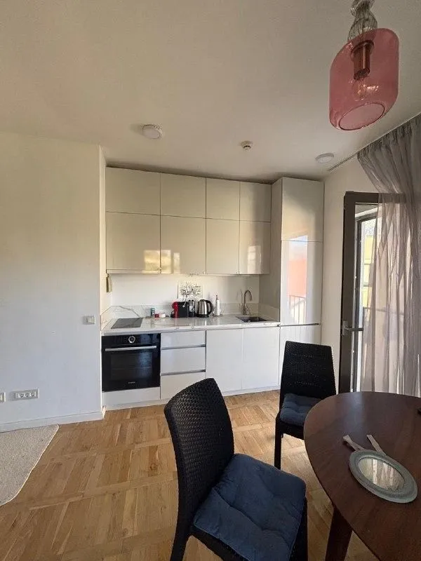 Small kitchen with white cabinets and a dining table.