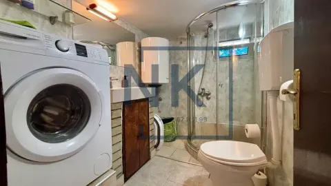 Smaller bathroom equipped with a shower cabin, sink, and washing machine. - image 9