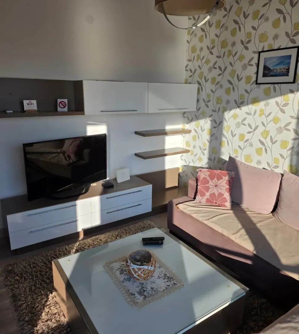 Living room with a sofa, TV unit and decorative wallpaper on the wall.