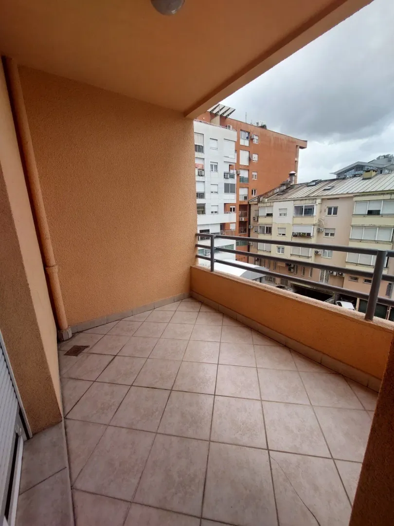 Unfurnished balcony with tiled flooring overlooking neighboring buildings.