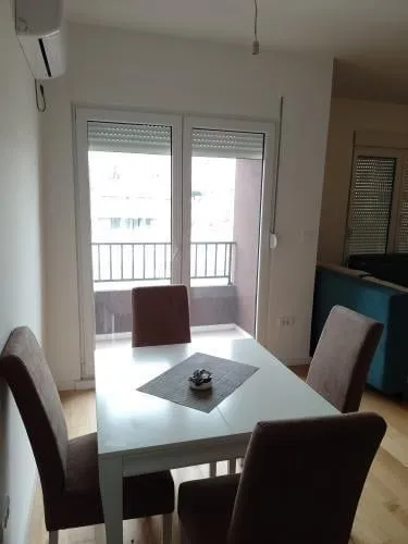 A dining table with four chairs next to the balcony exit.