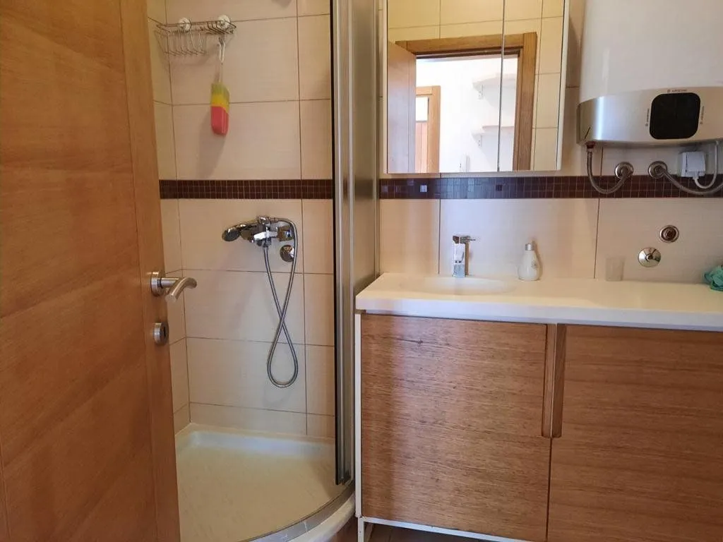 Bathroom equipped with a shower cabin, vanity unit with sink, and a water heater.