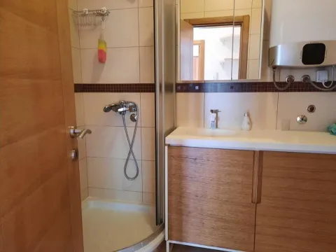 Bathroom equipped with a shower cabin, vanity unit with sink, and a water heater. - image 2