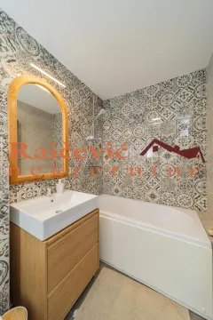 Bathroom equipped with a washbasin, mirror, and bathtub featuring decorative tiles. - image 4