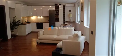 Dnevna soba povezana sa kuhinjom sa belom garniturom i drvenim podom. - image 3