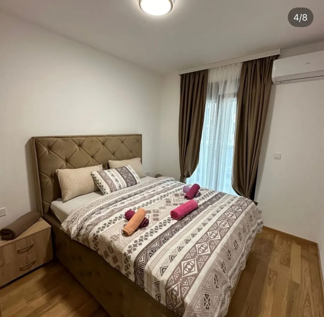 Furnished bedroom with a double bed and curtains.