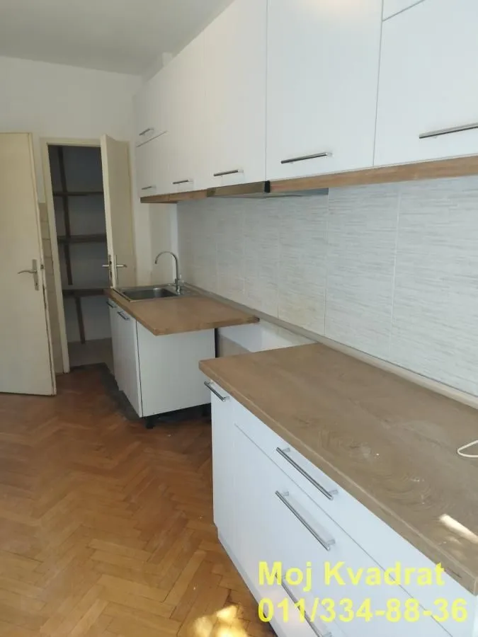 Small kitchen with white cabinets and a wooden countertop.