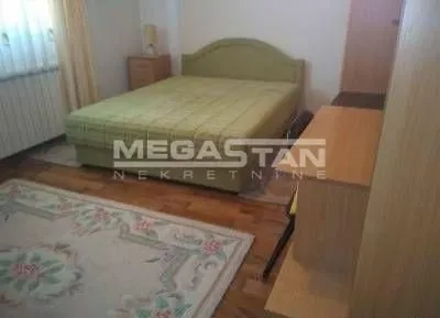 Nameštena spavaća soba sa bračnim krevetom, ormarom i radnim stolom.