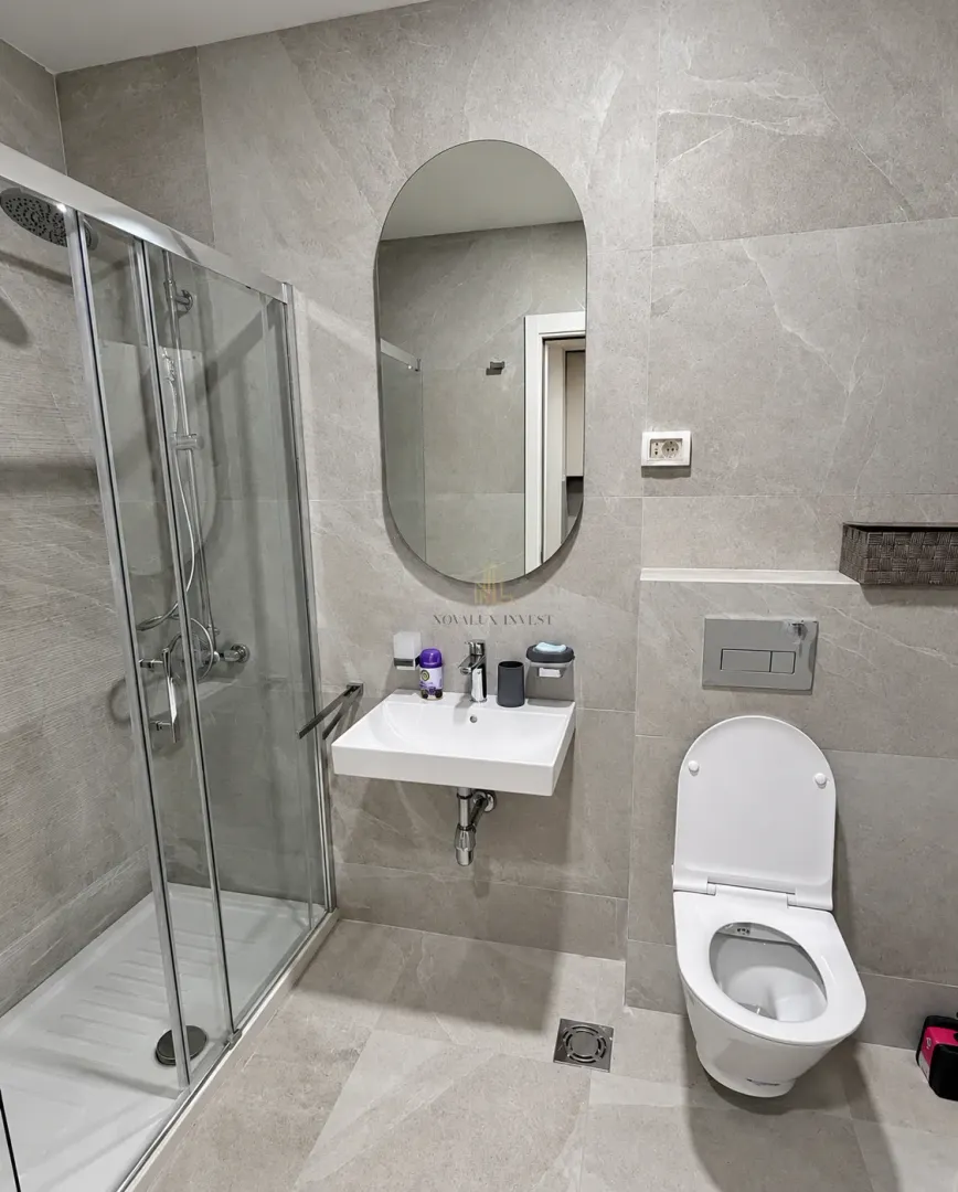Moderno opremljeno kupatilo sa tuš kabinom, umivaonikom i toaletom.