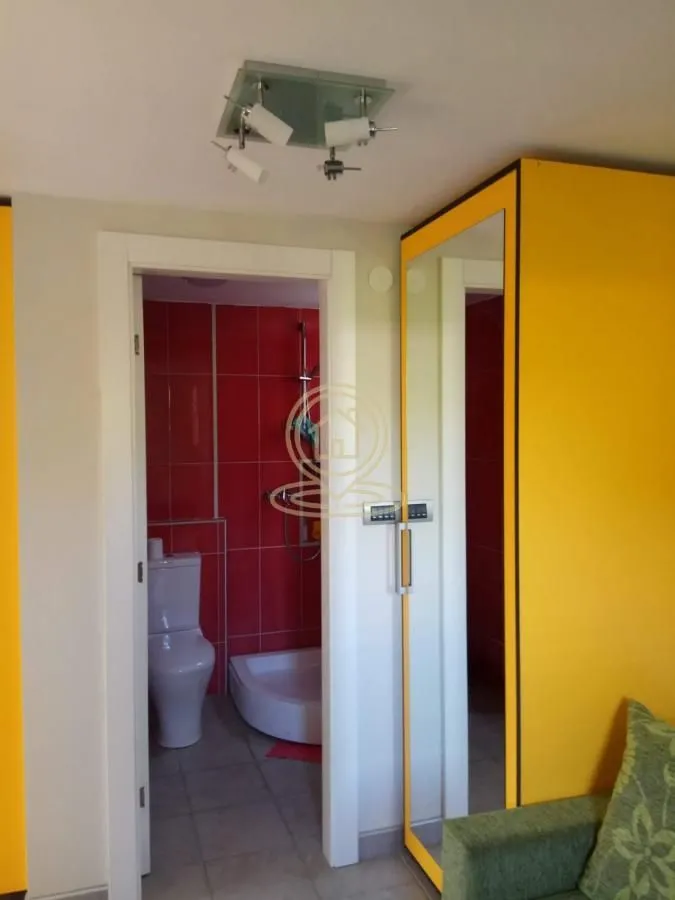 Pogled iz sobe na kupatilo sa crvenim pločicama i tuš kabinom.