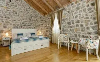 Bedroom with a double bed, stone walls, and a wooden ceiling. - image 7