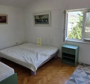 Svjetla spavaća soba sa krevetom, noćnim stočićem i prozorom. - image 5