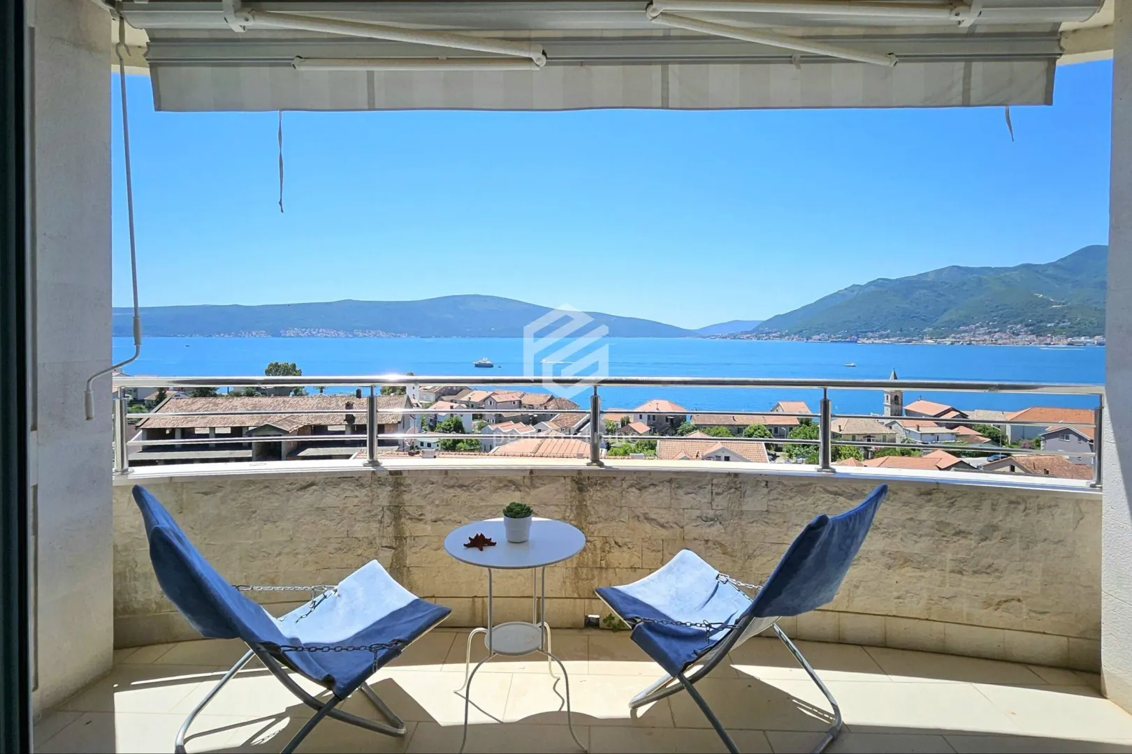 Natkriveni balkon sa garniturom za sjedenje i pogledom na more.